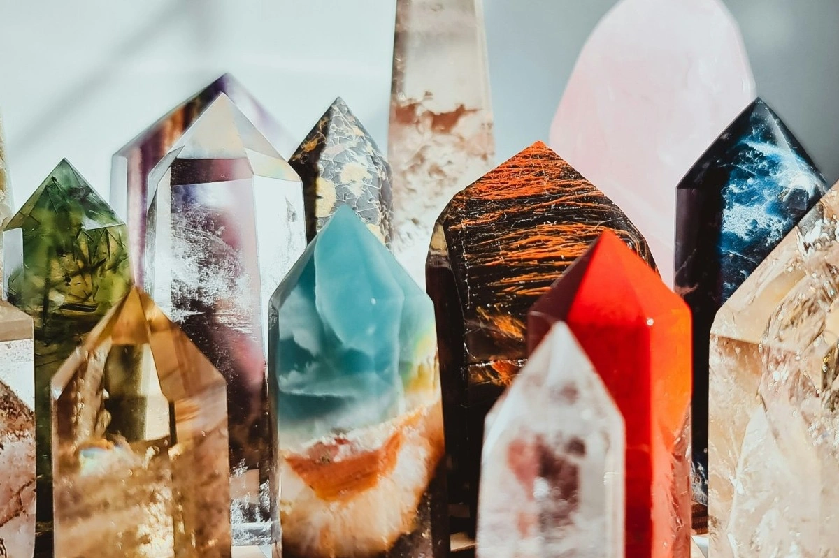 A close-up of colourful crystal points and towers crowded together (including carnelian, smoky quartz, fluorite, and rose quartz) catching the light