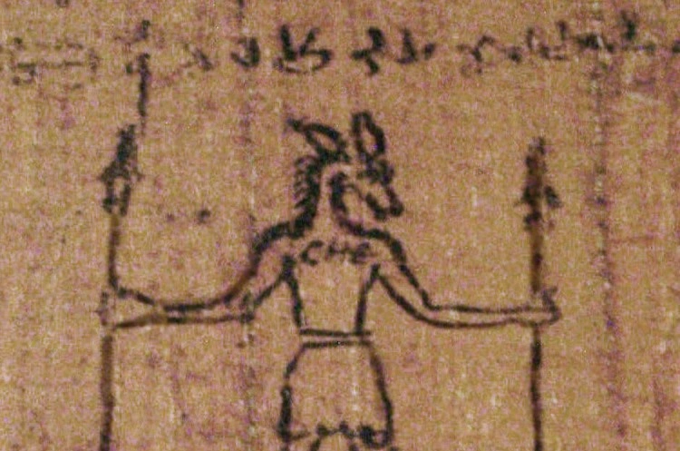 A fragment of aged papyrus covered in faint Greek script, resting on dark stone beside a small bronze figurine, a scatter of dried herbs, and a single lit clay oil lamp, photographed in warm amber light